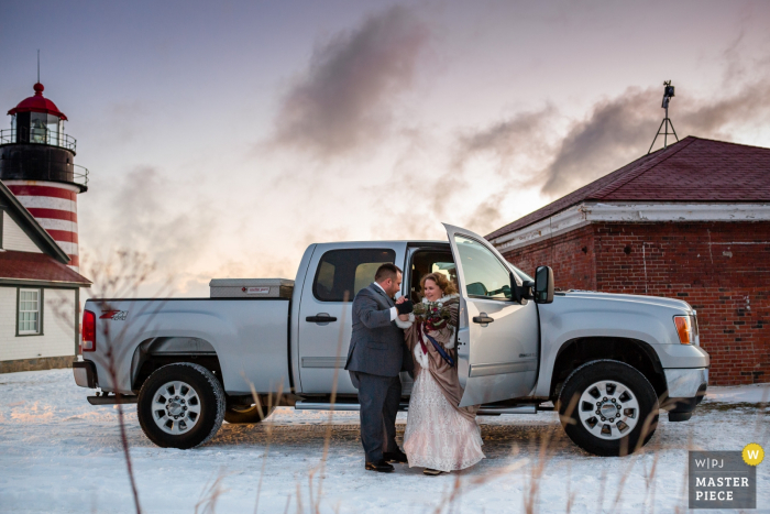 a bride and groom in front of a truck in the winter snow Lubec, Maine bride and groom in front of a truck after the wedding