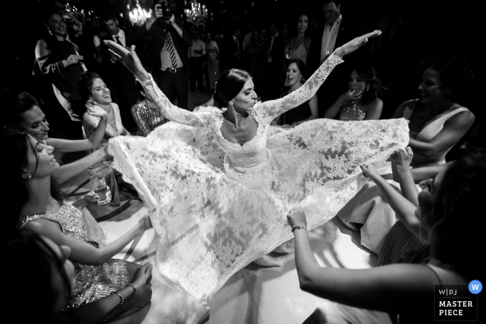 women guests lift up part of the brides dress at the reception Sao Paulo, Brazil guests lift up part of the brides dress at the wedding reception
