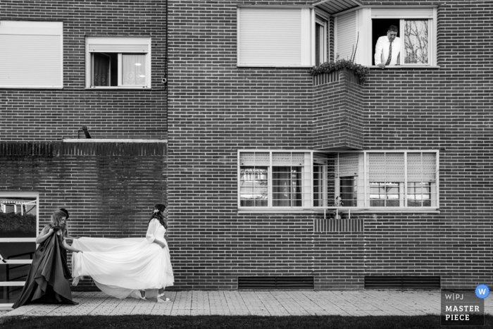 eine Braut, die mit Brautjungfer geht, die das Hochzeitskleid hält Braut Alcalá de Henares, Madrid, die mit der Brautjungfer hält das Hochzeitskleid geht