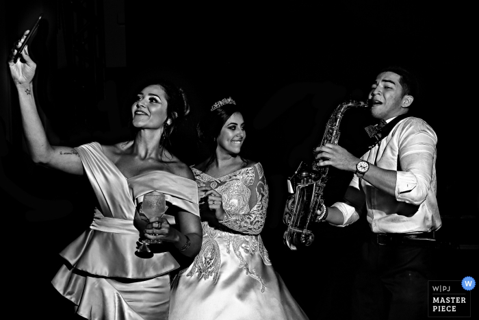 Photo: <a href="https://www.wpja.com/contests/2018-v04-photography-competition/best-wedding-photographers/2193891"> Claudia Amorim - Goiânia Goias </a> Demoiselle d'honneur de Goiania prend selfie avec le joueur de saxophone à la réception de mariage