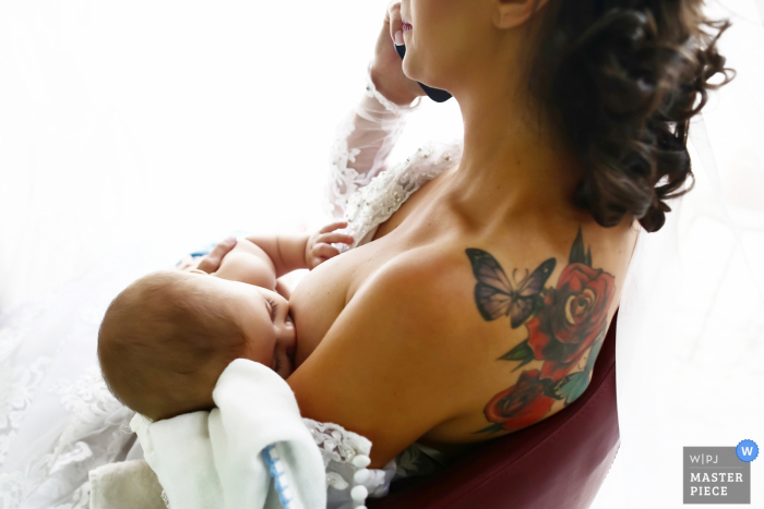 Goiania bridesmaid feeds her baby while on the phone before the wedding