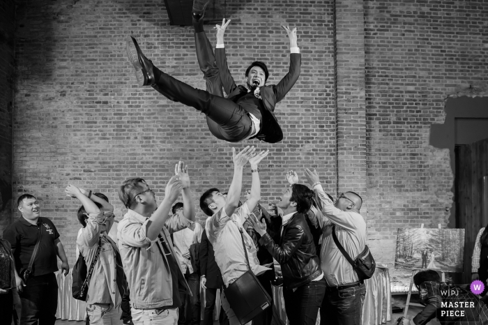Taiwan guests throw the groom into the air at the wedding reception