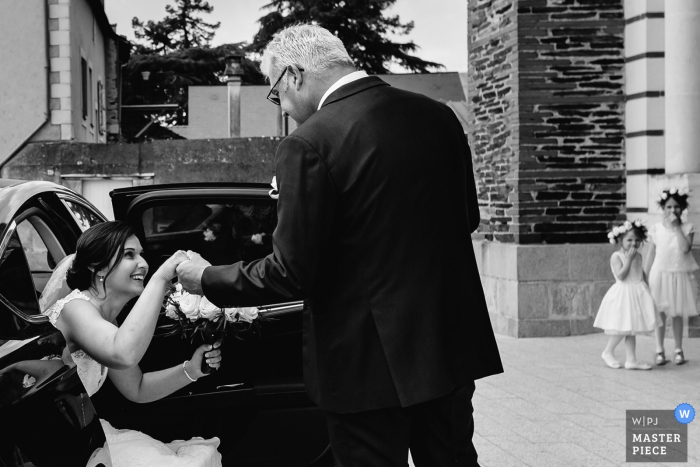 Angers brides father helping her get out of the car while in her dress