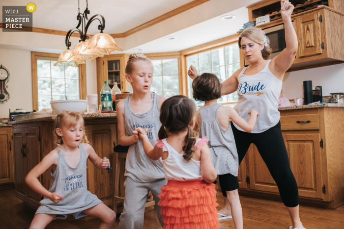 Photo by: <a href="https://www.wpja.com/contests/2018-v06-photography-competition/best-wedding-photographers/2206026">Dennis Crider - Loudonville Ohio</a> Photo of the bride warming up before the reception by dancing in the kitchen with kids at her house