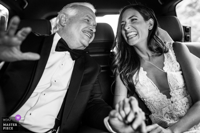 Photo by: <a href="https://www.wpja.com/contests/2018-v06-photography-competition/best-wedding-photographers/2206801">David Clumpner - Missoula Montana</a> Bride and her father laugh and hold hands while in the car at the wedding in Granada, Nicaragua