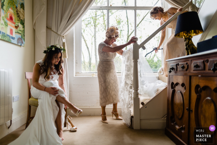 Photo by: <a href="https://www.wpja.com/contests/2018-v06-photography-competition/best-wedding-photographers/2212941">Annie Kheffache - Dun Laoghaire Dublin</a> The bride put her shoes on as others help with getting ready preparations in this wedding day photo from Meath, Ireland
