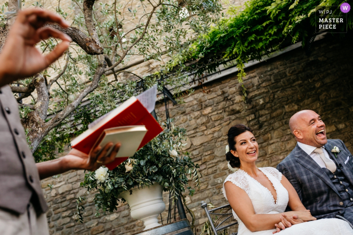 Photo by: <a href="https://www.wpja.com/contests/2018-v06-photography-competition/best-wedding-photographers/2214041">Leonard Walpot - Utrecht Utrecht</a> Ceremony Picture of the seated bride and groom laughing as the officiant speaks at this Italia wedding