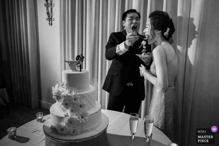 Photo by: <a href="https://www.wpja.com/contests/2018-v06-photography-competition/best-wedding-photographers/2215451">Chris Shum - Sunnyvale California</a> Bride and groom feed each other cake at the wedding reception at the Castlewood Country Club in Pleasanton