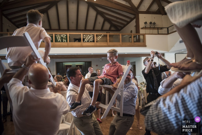 Photo by: <a href="https://www.wpja.com/contests/2018-v06-photography-competition/best-wedding-photographers/2215551">Stephanie Secrest - Arroyo Grande California</a> Guests lift up kids in chairs at the wedding reception in Moreaga, California