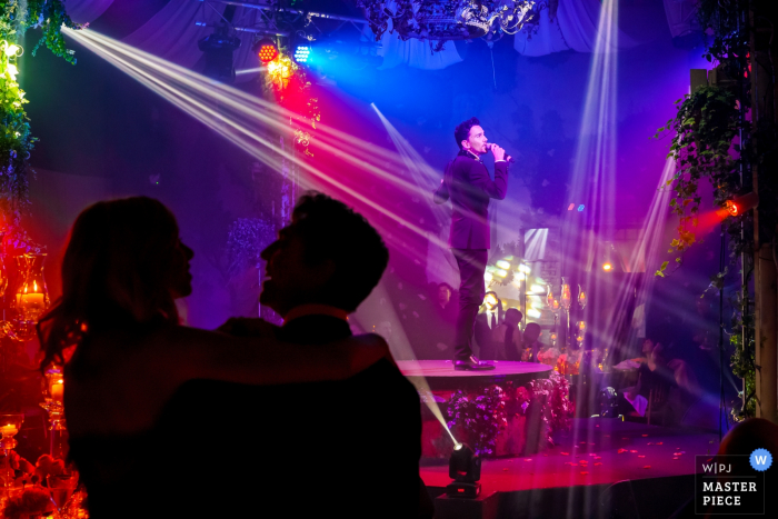 Braut und Bräutigam umarmen sich, während die Band beim Hochzeitsempfang im Castello di Tor Crescenza spielt