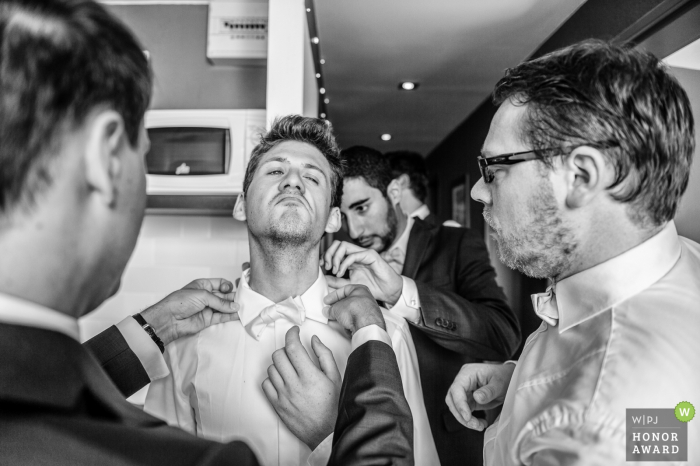 Foto von: <a href="https://www.wpja.com/contests/2018-v07-photography-competition/best-wedding-photographers/2225471"> Gaelle Le Berre - Mount Waverley Victoria </a> Die Trauzeugen helfen dem Bräutigam mit dem Hemdkragen und der Krawatte vor der Zeremonie in Camaret-sur-Mer, Frankreich