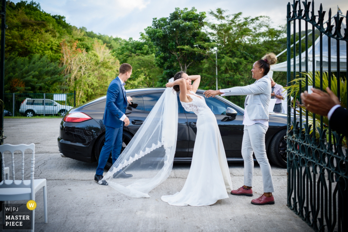 Foto von: <a href="https://www.wpja.com/contests/2018-v07-photography-competition/best-wedding-photographers/2225961"> Frederic Rejaudry - La Trinite </a> Foto im Freien der Braut vor dem Einsteigen in das Auto nach der Hochzeit in Les Trois Ilets, Martinique