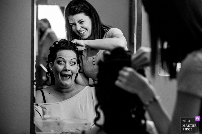 La novia de Hungría se hace el pelo en el espejo antes de la ceremonia de boda