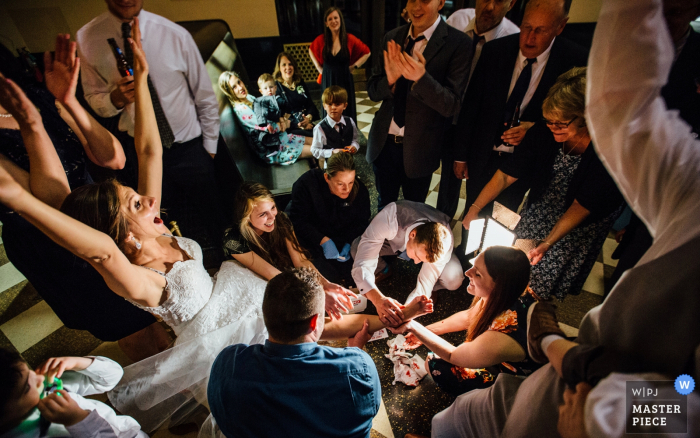 Foto door: <a href="https://www.wpja.com/contests/2018-v07-photography-competition/best-wedding-photographers/2229151"> Andrea Bibeault - Omaha Nebraska </a> De bruid wordt omringd door de gasten bij de huwelijksontvangst in Omaha, Nebraska