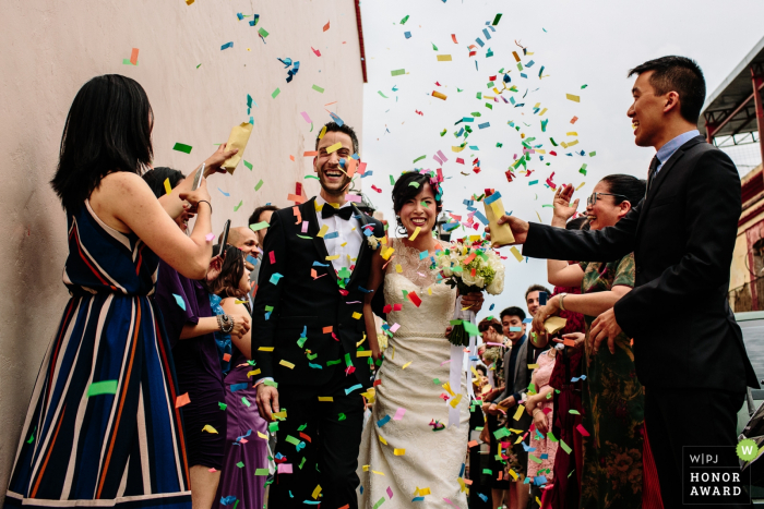 Oaxaca City, Oaxaca, Mexico bride and groom under a rainbow colored shower of confetti