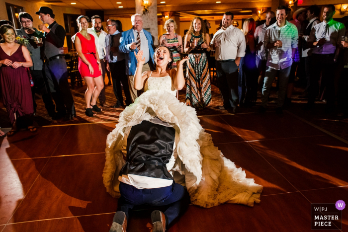 Foto door: <a href="https://www.wpja.com/contests/2018-v08/best-wedding-fotografen/2234421"> Shaunte Dittmar - Lake Tahoe California </a> Bruid lacht als de bruidegom de kousenband krijgt bij de bruiloftsreceptie in Lake Tahoe, Ca