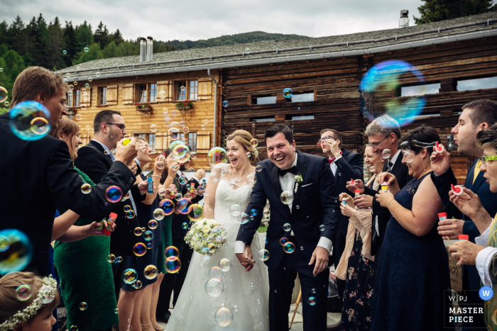 Photo by: <a href="https://www.wpja.com/contests/2018-v08/best-wedding-photographers/2235826">Andreas Feusi - Baar Zug</a> Guests blow bubbles outside at the bride and groom after the wedding in Guarda Val, Switzerland