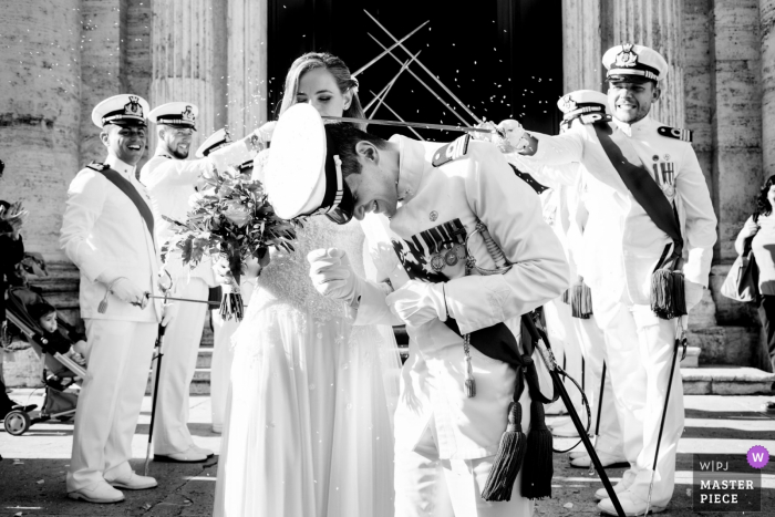 Traditional groom's military hat falling down with help from swords - Santa Maria in Vallicella, Rome, Italy