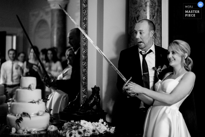 Bride holds a sword to cut the wedding cake at the reception in Carlow, Ireland