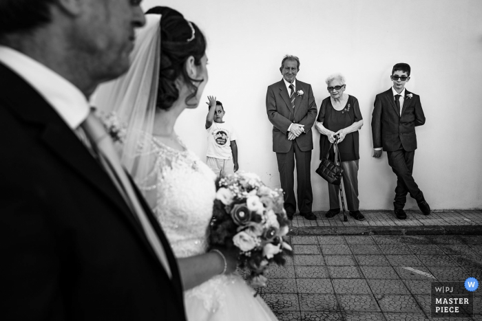 Los huéspedes de Calabria observan a la novia ya su padre antes de la ceremonia de boda.