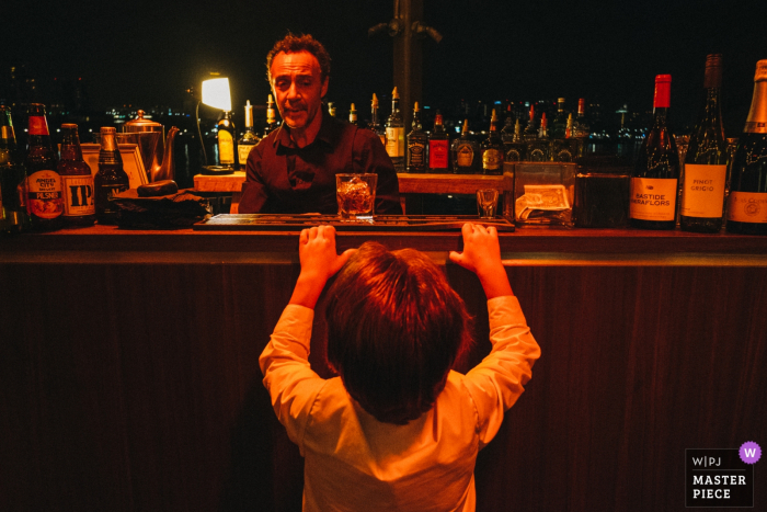 Little boy trying to look into the bar at the wedding in Long Beach, California, USA