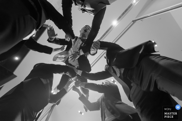 Groomsmen throw the groom into the air at the wedding reception in Taiwan