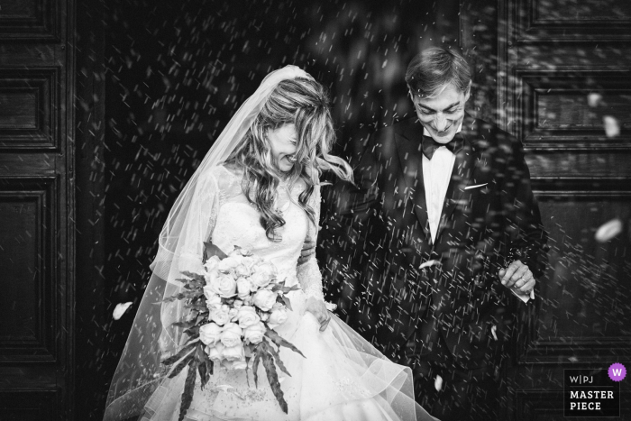the bride and groom smile as rice is throw at them Spoleto bride and groom smile as rice is throw at them after the wedding ceremony