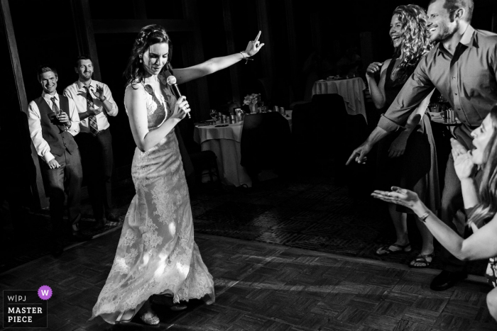 Foto door: <a href="https://www.wpja.com/contests/2018-v09/best-wedding-fotografen/2242856"> Shaunte Dittmar - Lake Tahoe California </a> Gasten lachen als de bruid zingt en danst bij de bruiloftsreceptie in Lake Tahoe, Ca