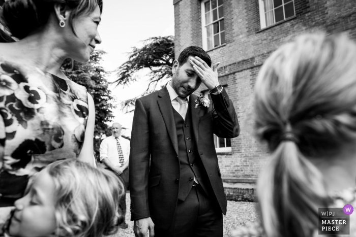 Groom wipes the sweat off of his forehead outside at the wedding in Reading, UK