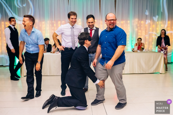 wedding guests laugh while the groom is blindfolded Slovenia guests laugh while the groom is blindfolded at the wedding reception