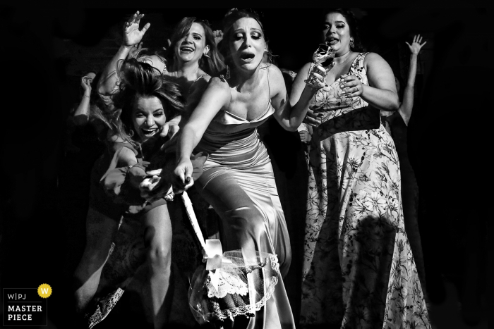 Black and white photo of women reaching for a bouquet by a Brazil wedding photographer in Goiânia.