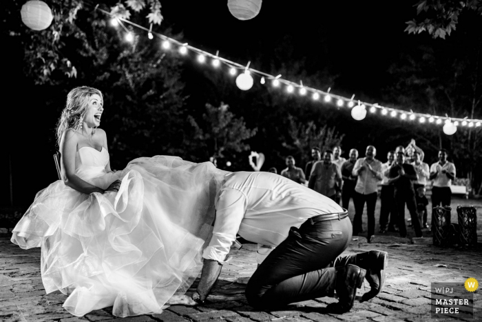 Foto: <a href="https://www.wpja.com/contests/2018-v11-photography-competition/best-wedding-photographers/2255741"> Hristina Handzhieva - Lovech </a> Bulgaria recepción de boda al aire libre en la noche - foto del novio que consigue la liga debajo del vestido de la novia.