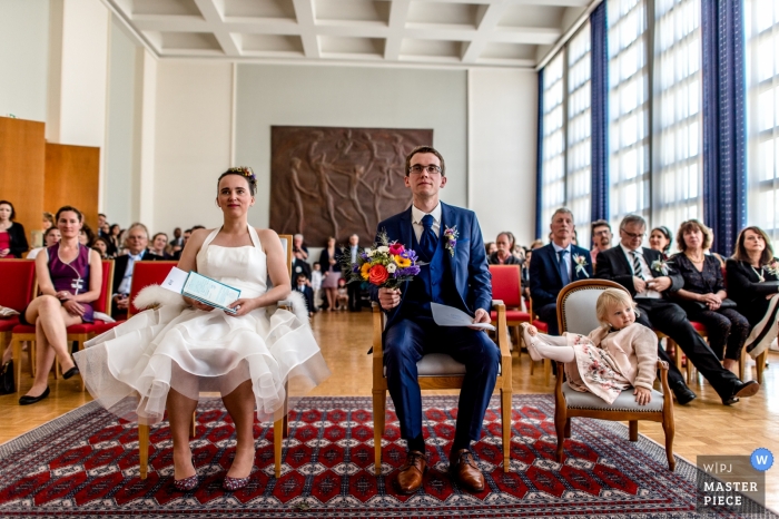 Brest, Frankrijk de foto van de huwelijksceremonie van bruid, bruidegom en bloemmeisjezitting als voorzitter met gasten achter hen.