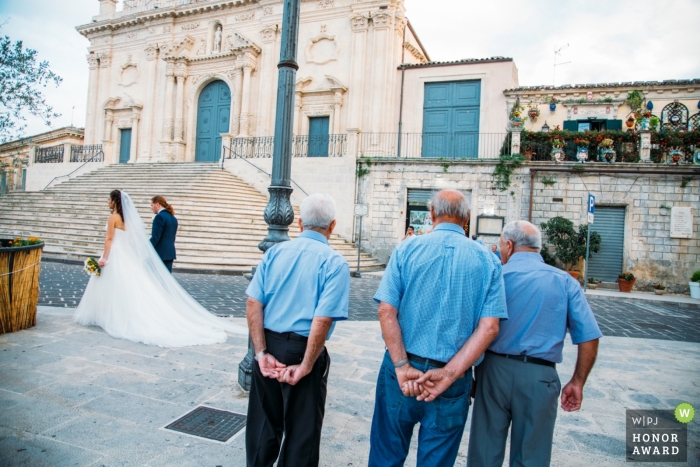 Sicilië mannen kijken naar de bruid en bruidegom wandelen langs de Palazzolo kerk waarin ze zijn getrouwd