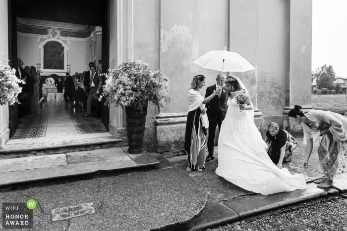 Foto por: <a href="https://www.wpja.com/contests/2018-v12-photography-competition/best-wedding-photographers/2277606"> Matteo Reni - Busto Arsizio Varese </a> Piacenza, Italia Novia bajo un paraguas bajo la lluvia preparándose para entrar a la iglesia para la ceremonia
