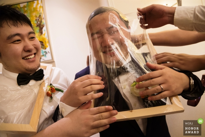 Foto: <a href="https://www.wpja.com/contests/2018-v12-Fotowettbewerb/best-wedding-photographers/2278161"> Ray Poon - ChongQing </a> Trauzeugen, die Spaß haben, dem Bräutigam während der traditionellen Türspiele in China zu helfen