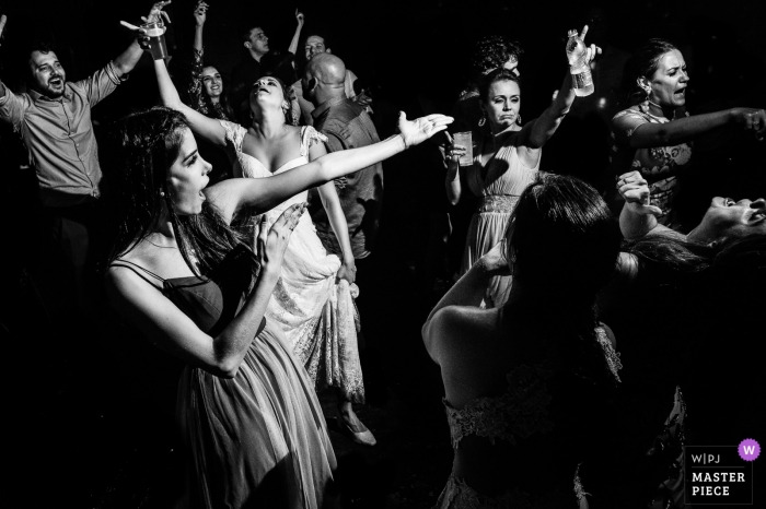 São Carlos Wedding Photojournalist | the bride is surrounded by dancing female wedding guests on the dance floor in and this black-and-white reception photo