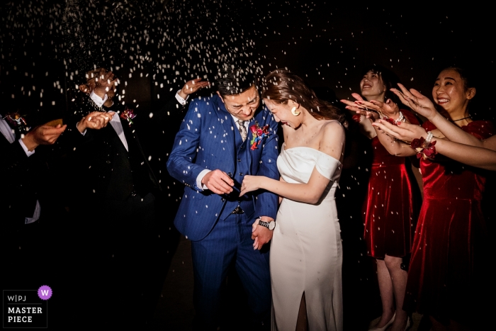 Photo by: <a href="https://www.wpja.com/contests/2018-v13/best-wedding-photographers/2286071">Vincent Mu - De Zhou </a> Shandong Wedding Photojournalist | the bride and groom are showered with confetti by guests as they exit the wedding reception at night