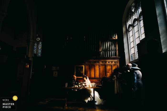 Ss Peter and Paul Kettering - Bride and groom signing the register below wonderful window light