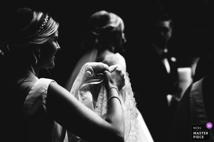 Photo by: <a href="https://www.wpja.com/contests/2018-v13/best-wedding-photographers/2288691">Hannah Hall - Corby Northamptonshire</a> Bridesmaid carries bride's dress at Church, Bromsgrove