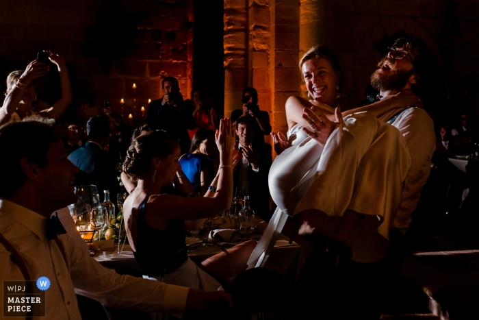 Spain Wedding Photojournalist | the bride is carried by her husband at this reception party