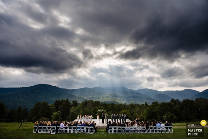 Photo by: <a href="https://www.wpja.com/contests/2018-v13/best-wedding-photographers/2289686">Megan Hannah - Lincoln Vermont</a> Stowe, VT Wedding Photojournalism | rays of light Stream through storm clouds overhead at this outdoor new England wedding ceremony