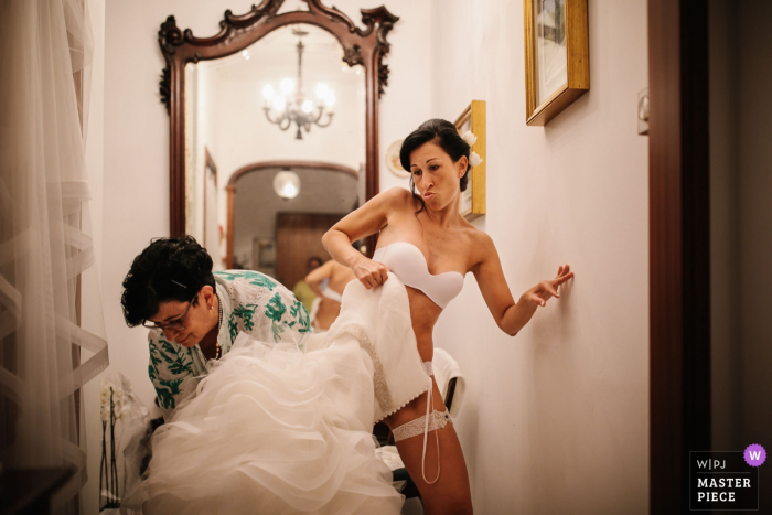 Foto: <a href="https://www.wpja.com/contests/2018-v14-Fotowettbewerb/best-wedding-photographers/2295961"> Julian Kanz - Portofino Genova </a> Portofino Hochzeitsfotojournalist | Genua-Braut, die mit etwas Hilfe in ihr Hochzeitskleid tritt - Farbphotographie