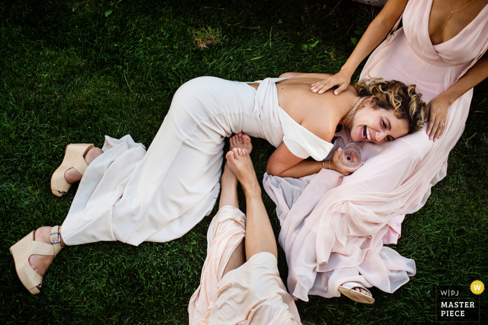 Falmouth, MA bridesmaids have fun and laugh with the bride on the grass