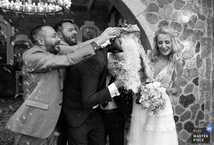 Photo by: <a href="https://www.wpja.com/contests/2018-v15/best-wedding-photographers/2304881">Panagiotis Kounoupas - Palaio Faliro </a> Attica Wedding Photojournalist | Athens groom gets showered with a heavy dose of rice by two friends after the wedding ceremony