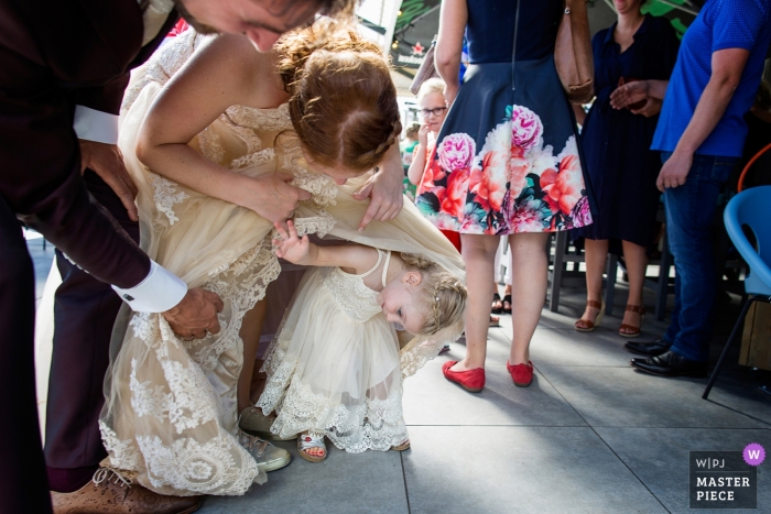 Photo by: <a href="https://www.wpja.com/contests/2018-v15/best-wedding-photographers/2306101">Jess van Ruiven - Heerhugowaard Noord Holland</a> Enkhuizen Het Station wedding photograph of young flower girl hiding under the bride's dress.