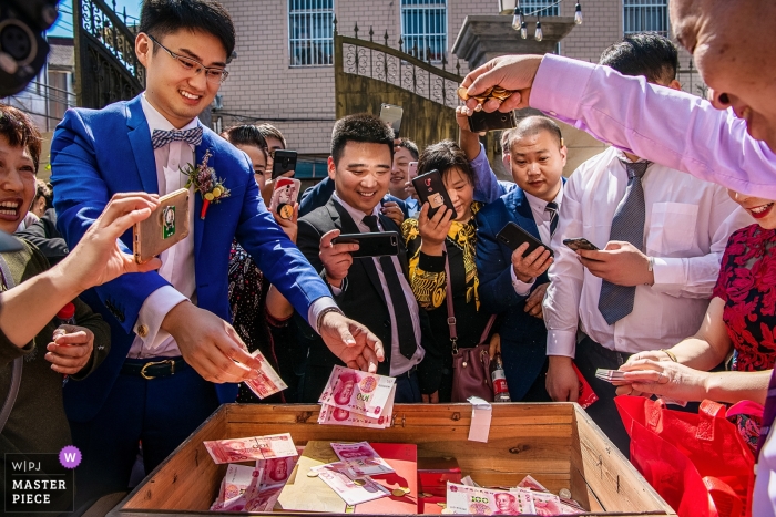 Photo by: <a href="https://www.wpja.com/contests/2018-v15/best-wedding-photographers/2308086">Moana Wu - Shanghai </a> Photograph of wedding guests and family in the China throwing money into a wooden box