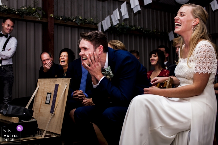 Foto door: <a href="https://www.wpja.com/contests/2018-v15-photography-competition/best-wedding-photographers/2312251"> Hessam Seyedi - Groningen </a> Het paar van Groningen lachend tijdens hun huwelijksontvangst bij de diavoorstelling met foto's van voorbij bruidegoms