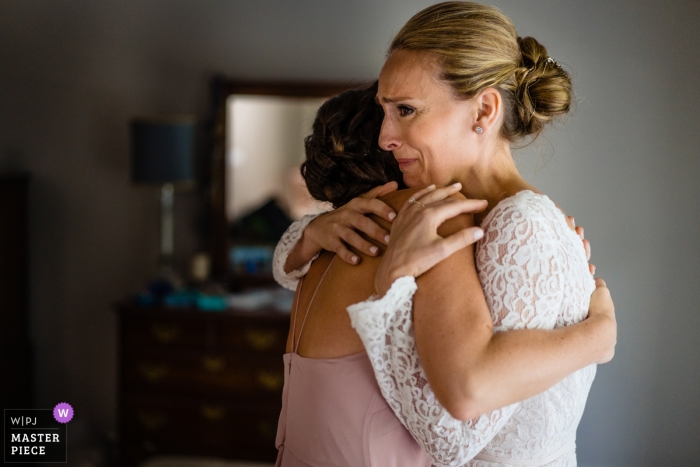 Photo by: <a href="https://www.wpja.com/contests/2018-v15/best-wedding-photographers/2313581">Nicole Chan - Quincy Massachusetts</a> Wedding photo in Boston of the bride receiving a hug from a friend - client home photography