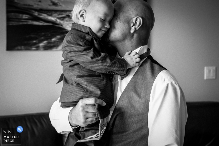 Documentary wedding photography at Alberta - Man holding and hugging a small ring bearer in a suit